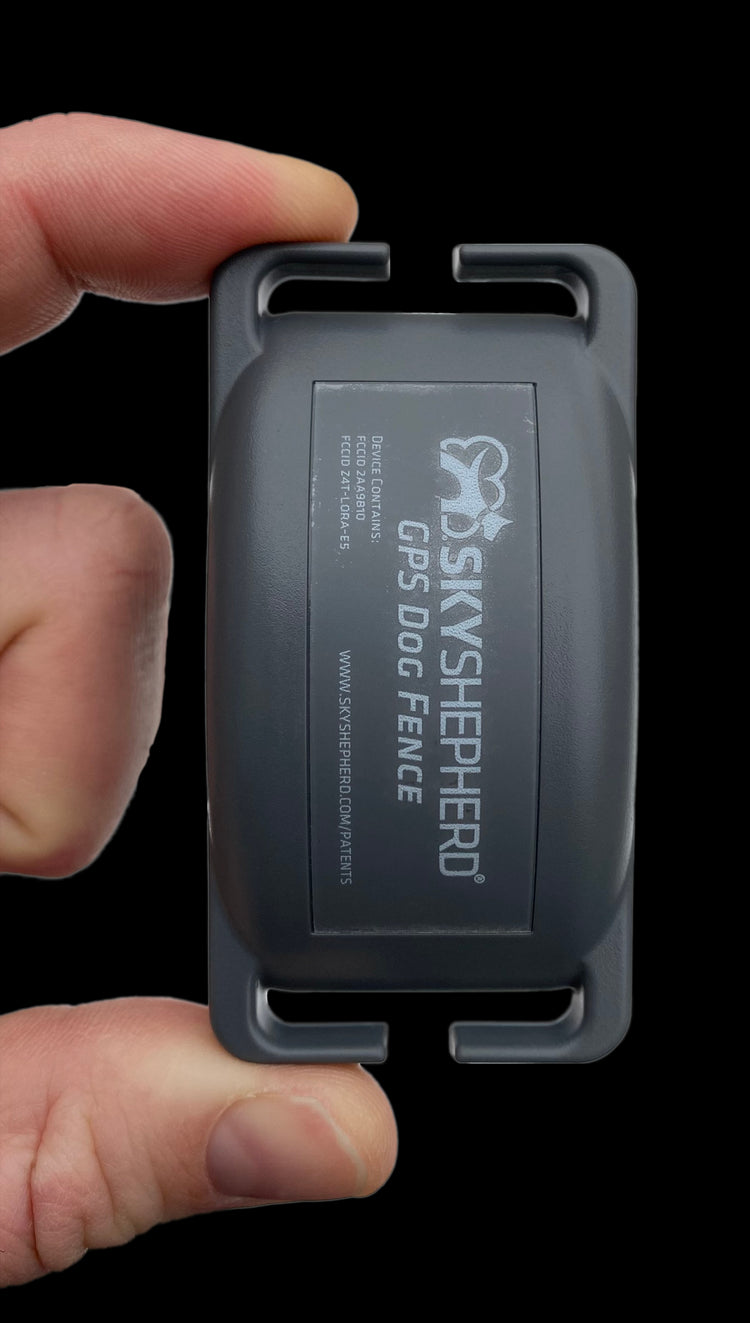 A hand easily holds the SkyShepherd GPS collar unit between index finger and thumb.